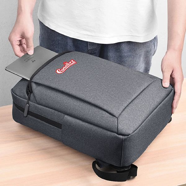 Person sliding a laptop into the top opening of a grey oxford laptop backpack printed with a logo