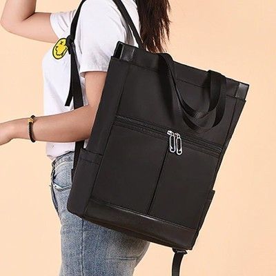 Woman wearing the black XE backpack by its shoulder straps, printed with a sample logo