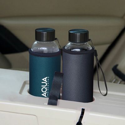 Two glass bottles in teal and grey neoprene sleeves, one printed with a logo, standing in a car cup holder