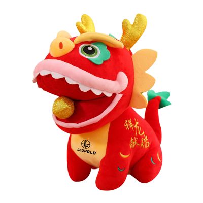 A red dragon soft toy with gold horns and a fabric mane, holding a small ball and printed with a logo on the leg.