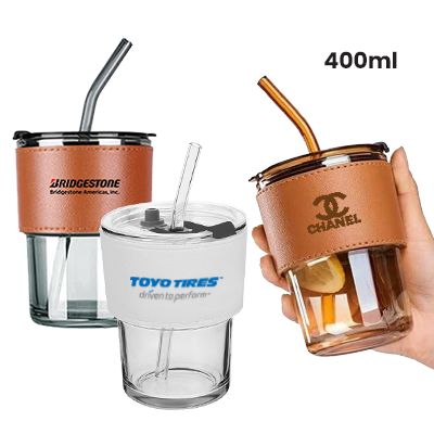 Glass mugs in tan, blue and brown PU sleeves with straws in place, one of them held in a hand, captioned 400ml.