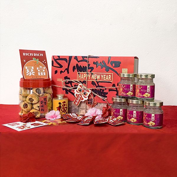 Red patterned gift box behind stacked cookie jars, small jars with pink lids and red packet folders on a red cloth.