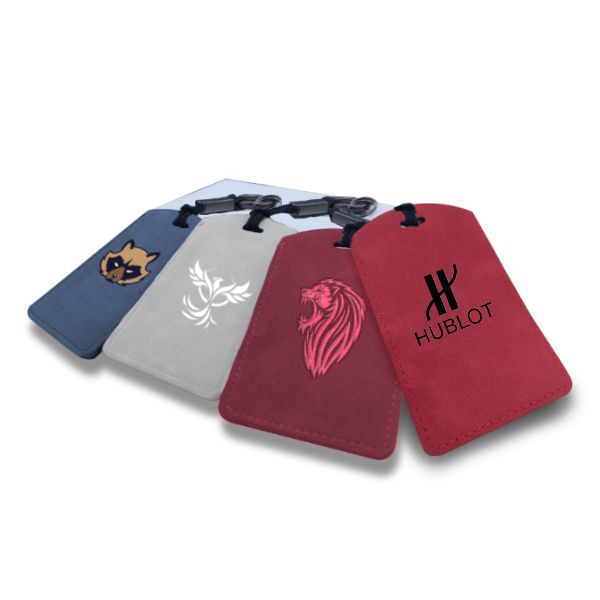 Four suede look ID tags fanned out in navy, pale grey, dark red and deep red, each hanging from a black cord with a metal ring.