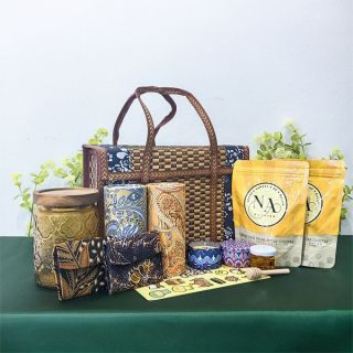 Rattan basket with a glass canister under a wooden lid, batik tissue box and pouches, candle tins and a yellow snack pouch.