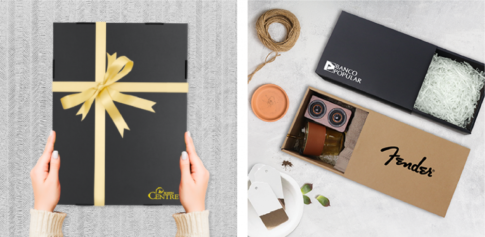 Black gift box tied with a gold ribbon, and a two-compartment kraft gift box laid out with shredded paper filler and gift items
